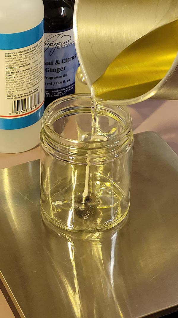 picture of the measuring process for pouring in the melted soy wax into the prepared candle jar